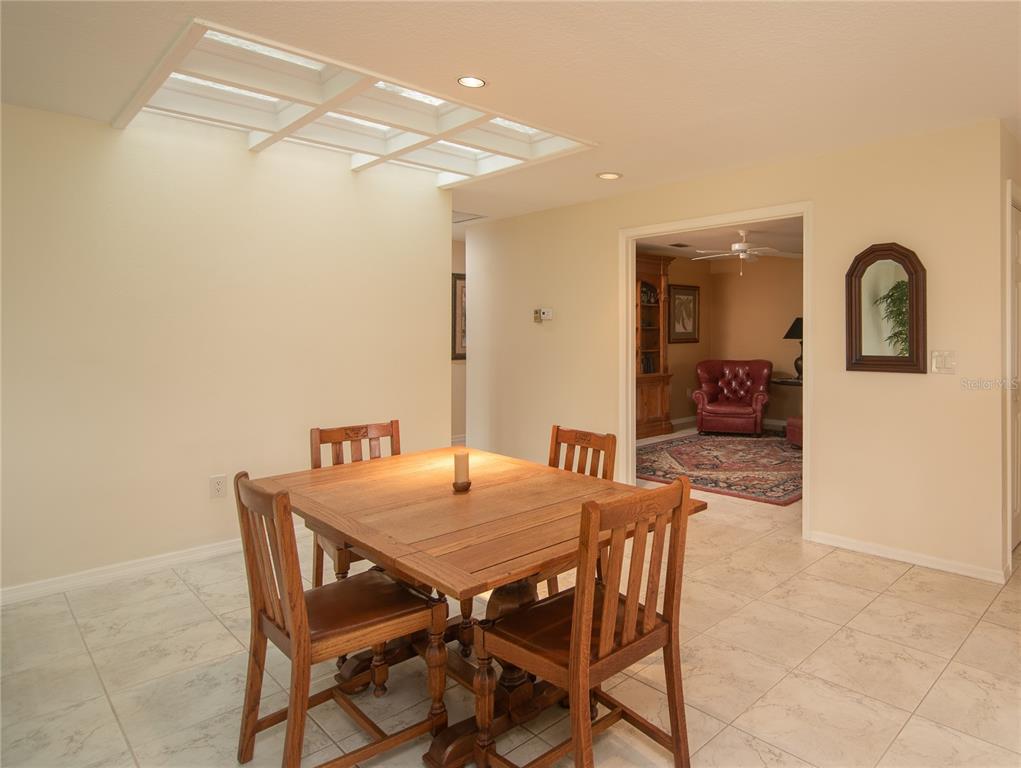 A dining area with a wooden table and chairs sits beneath a large skylight — 7403 CARNOUSTIE DRIVE UNIT 7D, SARASOTA, FL