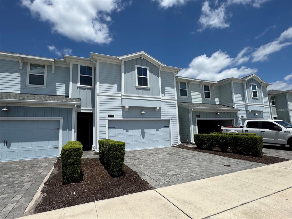 A light blue two-story townhouse features a two-car garage and a paved driveway — 4915 TRIBUTE TRAIL, KISSIMMEE, FL