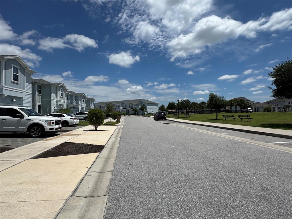A street view shows a row of townhomes next to a park with benches — 4915 TRIBUTE TRAIL, KISSIMMEE, FL