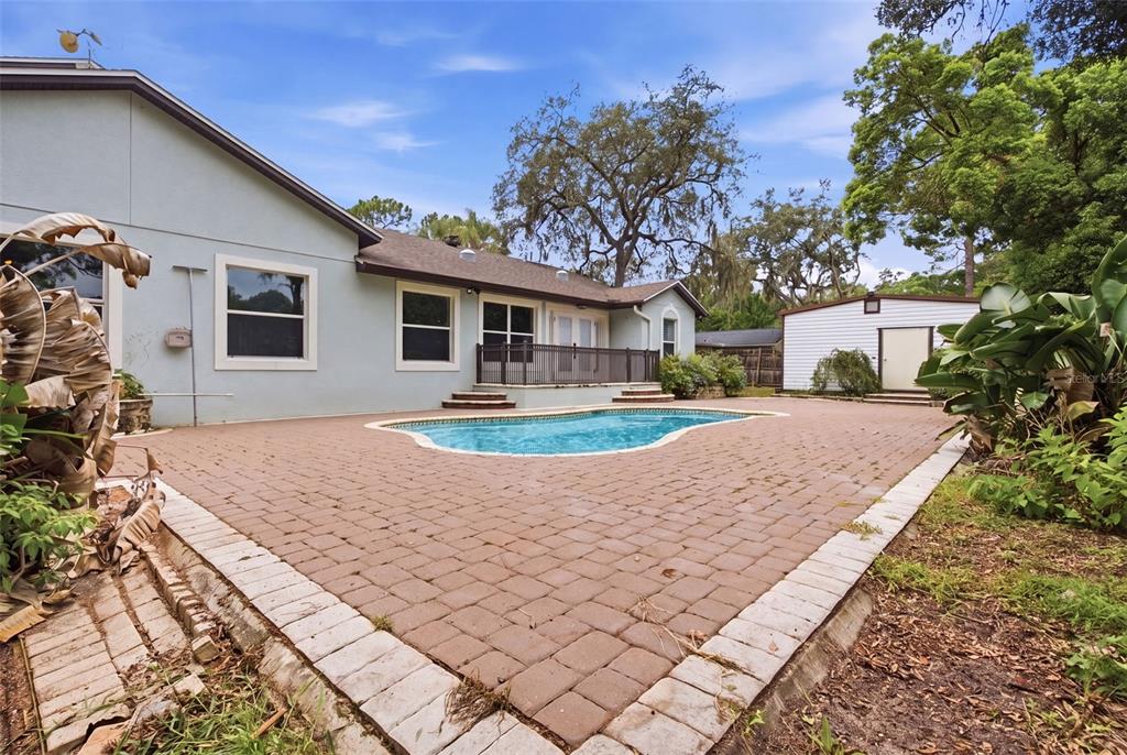 A backyard features a brick paver patio, an in-ground swimming pool, and a detached shed — 164 E GOODHEART AVENUE, LAKE MARY, FL