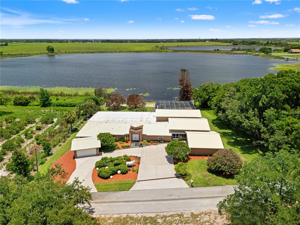 An aerial view shows a house with a metal roof, pool cage, and large lake — 775 S ILAKEE AVENUE, LAKE ALFRED, FL