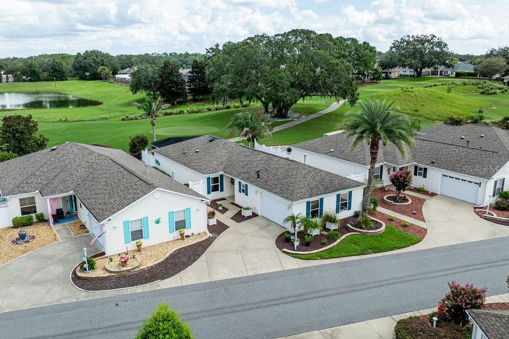 An aerial view shows two single-story houses with white siding and driveways overlooking a golf course — 8975 SE 168TH TAILFER STREET, THE VILLAGES, FL