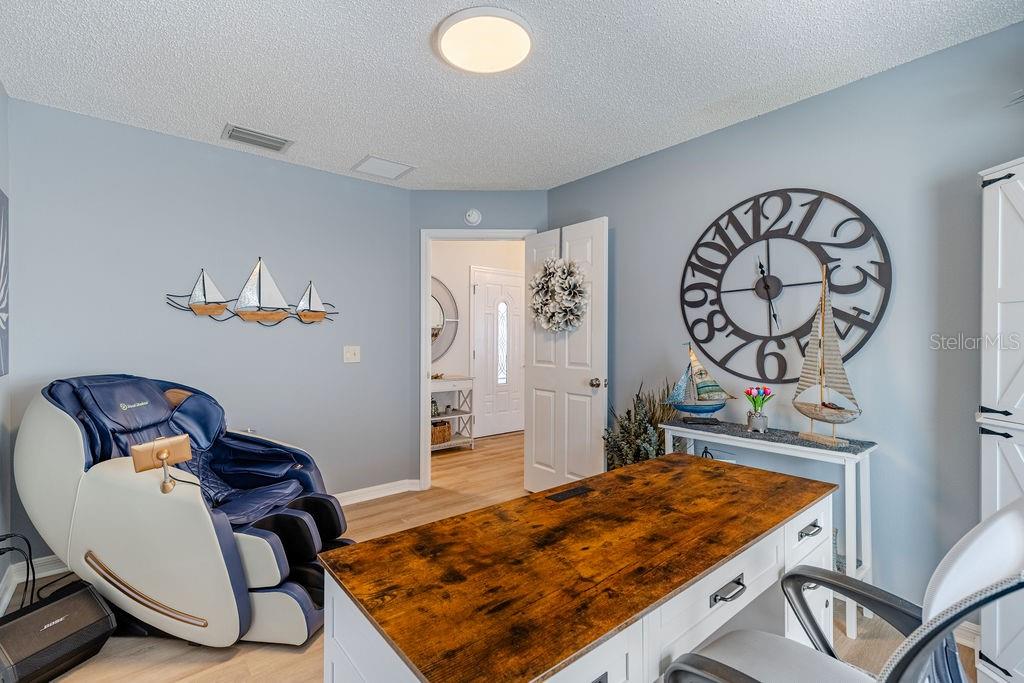 A home office features a massage chair, a wooden desk, and a large wall clock — 8975 SE 168TH TAILFER STREET, THE VILLAGES, FL