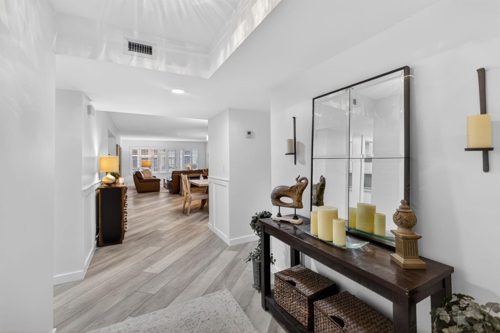 A bright entryway features wood-look flooring, a console table with decor, and a large mirror — 19149 SE Sea Turtle Court # 105, Jupiter FL 33469, JUPITER, FL