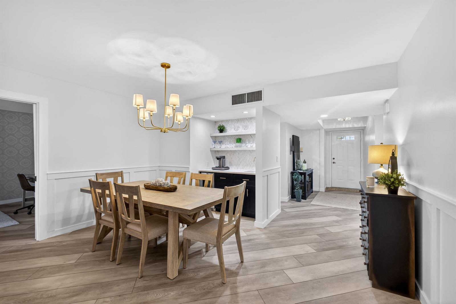 A dining room features a wooden table, a wet bar, and light wood-look flooring — 19149 SE Sea Turtle Court # 105, Jupiter FL 33469, JUPITER, FL