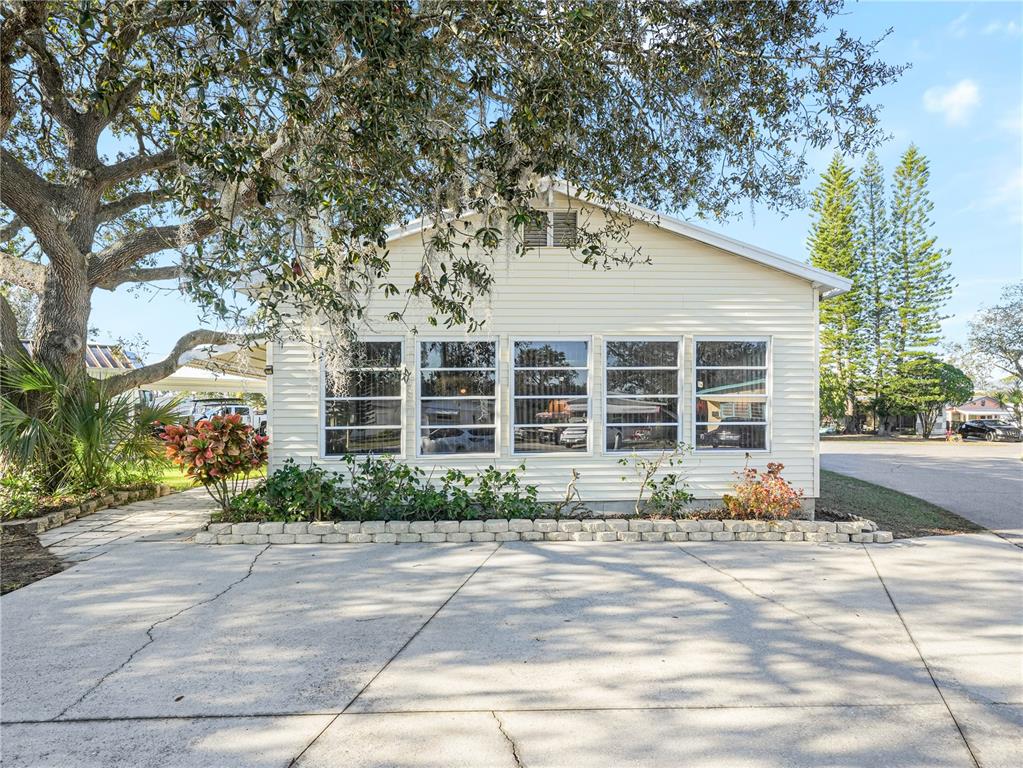 A light-colored house with a large front window wall and a concrete driveway — 27 SADDLEBAG TRAIL S, LAKE WALES, FL