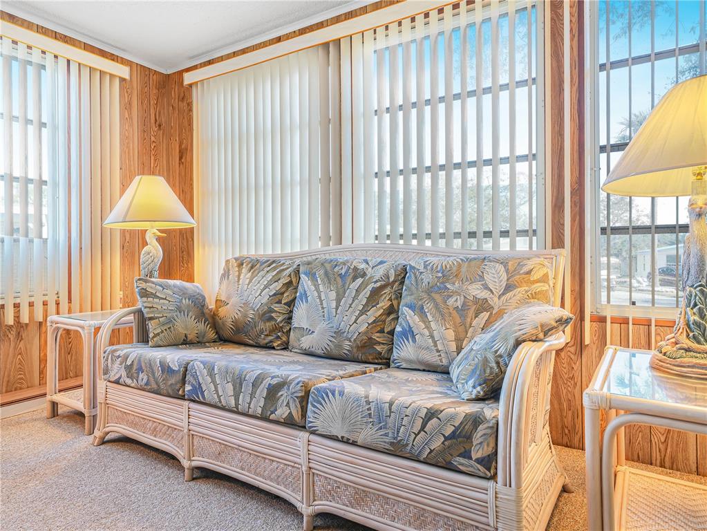 A living room features a tropical-print sofa, two end tables with lamps, and wood-paneled walls — 27 SADDLEBAG TRAIL S, LAKE WALES, FL