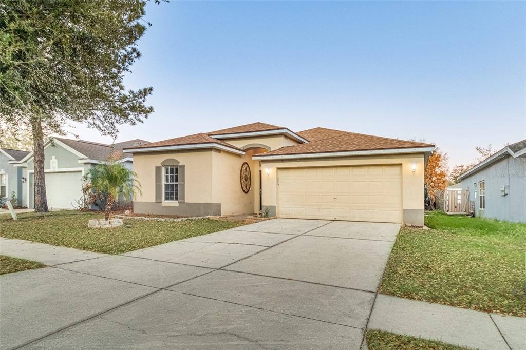 A single-story house with a beige stucco exterior, a two-car garage, and a concrete driveway — 763 STAR POINTE DRIVE, SEFFNER, FL