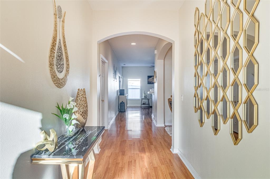 A hallway features hardwood floors, a marble-topped console table, and a large gold-framed geometric mirror — 763 STAR POINTE DRIVE, SEFFNER, FL
