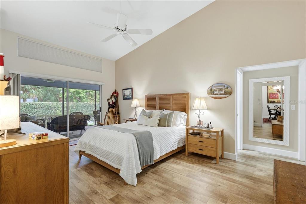 A bedroom with a vaulted ceiling, wood flooring, a queen bed, and a sliding glass door — 2644 MOSS OAK DRIVE UNIT 47, SARASOTA, FL