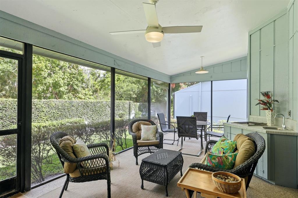 A screened-in patio features wicker furniture, a ceiling fan, and an outdoor kitchenette area — 2644 MOSS OAK DRIVE UNIT 47, SARASOTA, FL