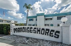 A white wall with the text Paradise Shores stands in front of a multi-story apartment building — 5357 81ST STREET N UNIT 24, ST PETERSBURG, FL