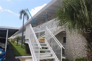 An exterior view of a multi-story apartment building with a white staircase and covered walkway — 5357 81ST STREET N UNIT 24, ST PETERSBURG, FL