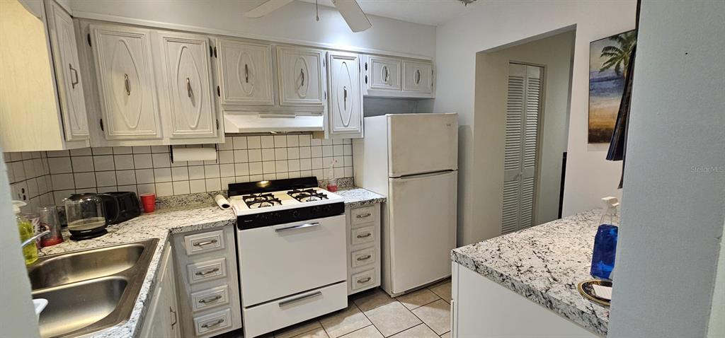 A kitchen features white cabinets, granite countertops, a white stove, and a white refrigerator — 5357 81ST STREET N UNIT 24, ST PETERSBURG, FL