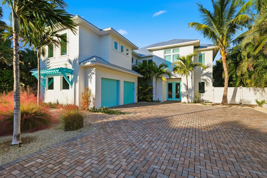 A two-story white house with a brick driveway, turquoise garage doors, and palm trees — 50 N SHORE DRIVE, ANNA MARIA, FL