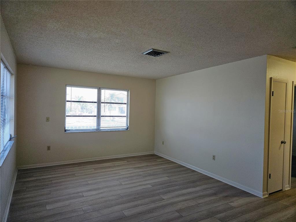 An empty room with light-colored walls, wood-look flooring, and a window with blinds — 360 137TH AVENUE CIRCLE UNIT 360, MADEIRA BEACH, FL