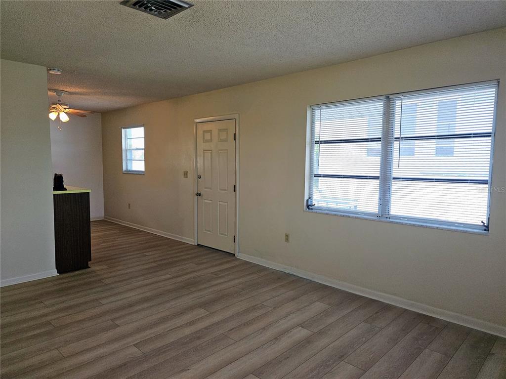 An interior view of a living room with light-colored walls, wood-look flooring, and a door — 360 137TH AVENUE CIRCLE UNIT 360, MADEIRA BEACH, FL