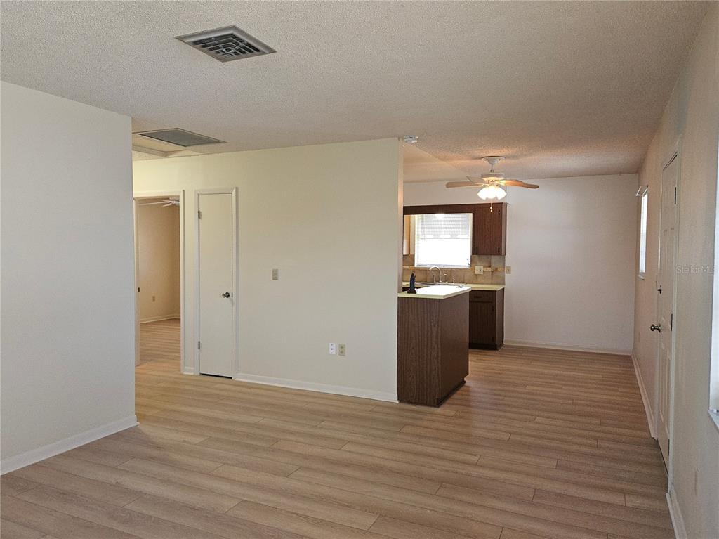 An open-concept living area features light wood-look flooring and a kitchen with dark cabinetry — 360 137TH AVENUE CIRCLE UNIT 360, MADEIRA BEACH, FL