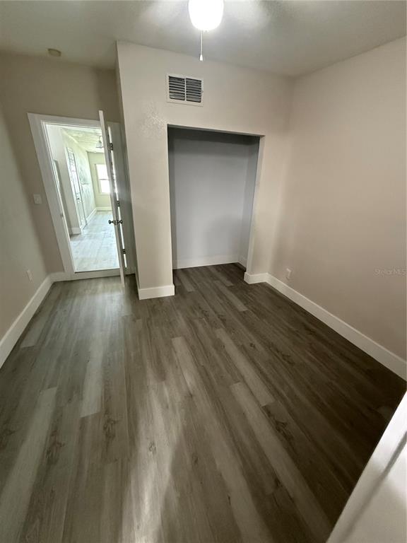 A bedroom with light-colored walls, wood-look flooring, a ceiling fan, and an open closet — 5612 LARIMER DRIVE, TAMPA, FL