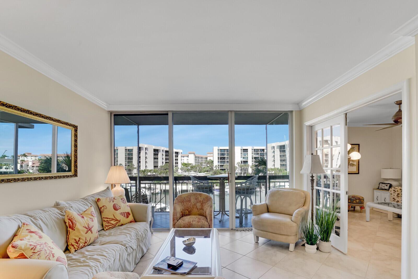 A living room with tile floors, a beige sofa, and a balcony overlooking a marina — 2687 N Ocean Boulevard # 305, Boca Raton FL 33431, BOCA RATON, FL