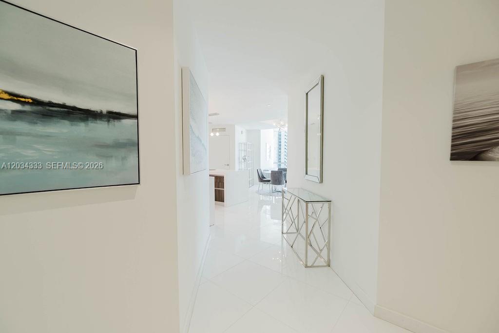 A white hallway features a console table, a tall mirror, and artwork on the walls — 851 NE 1st Ave # 2303, Miami FL 33132, MIAMI, FL