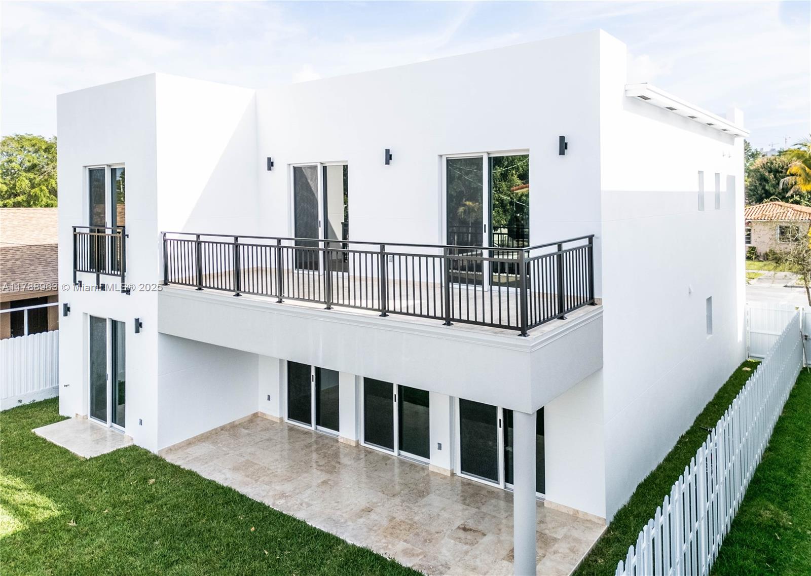 A two-story white modern house features a large balcony, sliding glass doors, and a patio — 910 SW 24th Rd, Miami FL 33129, MIAMI, FL