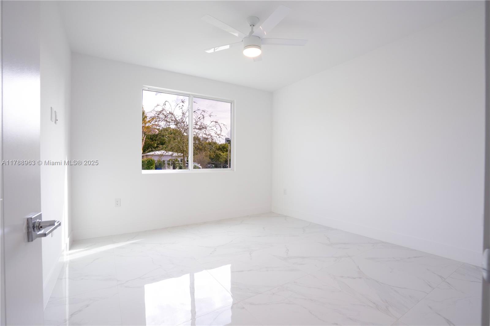 An empty bedroom features white walls, a ceiling fan, and polished white marble-look tile flooring — 910 SW 24th Rd, Miami FL 33129, MIAMI, FL