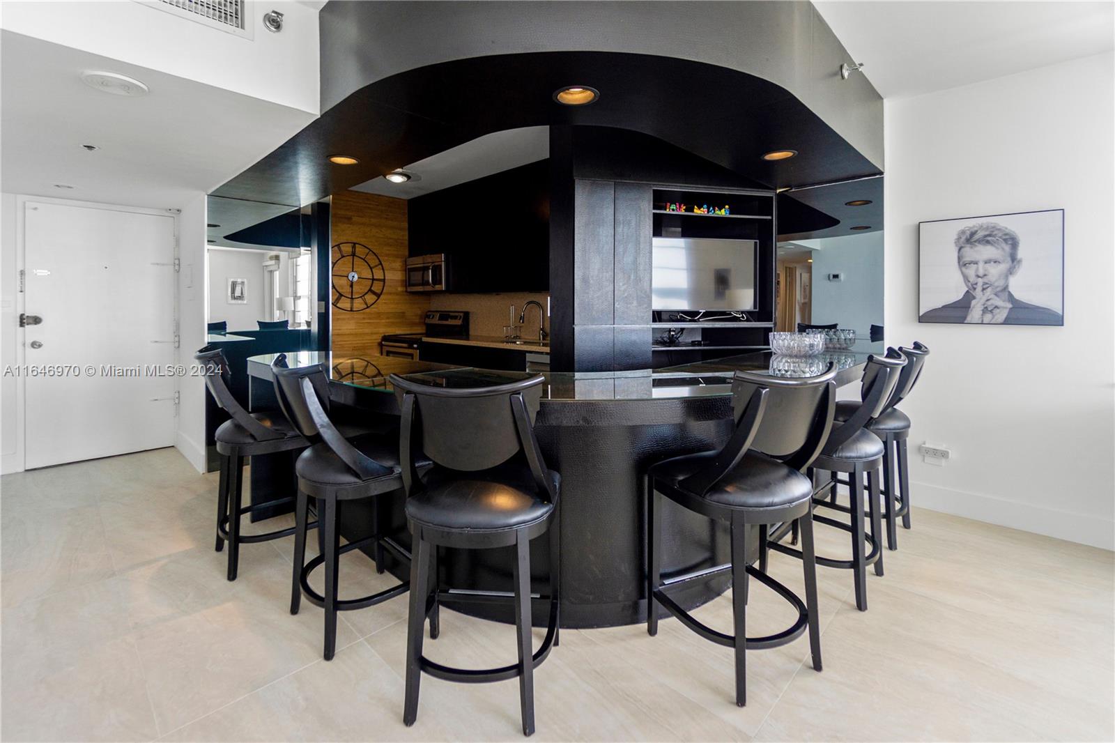 A curved black bar with stools sits in a modern kitchen with light flooring — 100 Lincoln Rd # 548, Miami Beach FL 33139, MIAMI BEACH, FL