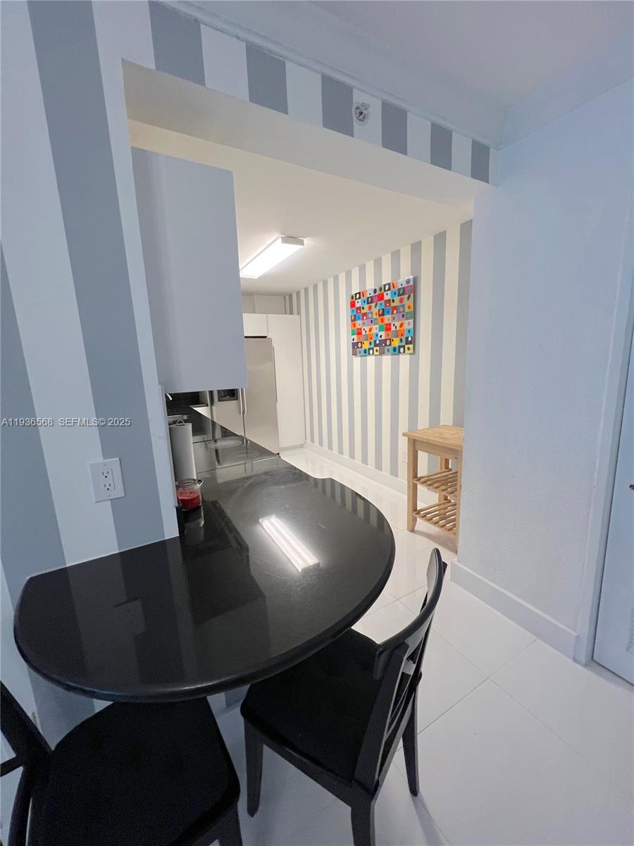 A kitchen features a black curved countertop, white striped walls, and white tile flooring — 401 69th St # 304, Miami Beach FL 33141, MIAMI BEACH, FL