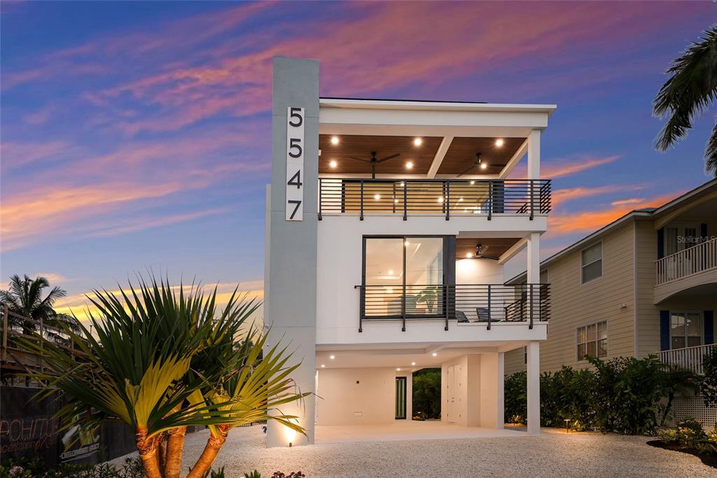 A modern three-story house with a white exterior, balconies, and a ground-level carport — 5547 AVENIDA DEL MARE, SARASOTA, FL