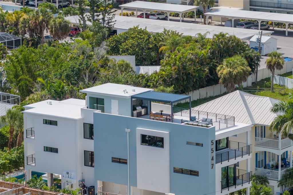 An aerial view of a modern multi-story house featuring a rooftop terrace with a pergola — 5547 AVENIDA DEL MARE, SARASOTA, FL