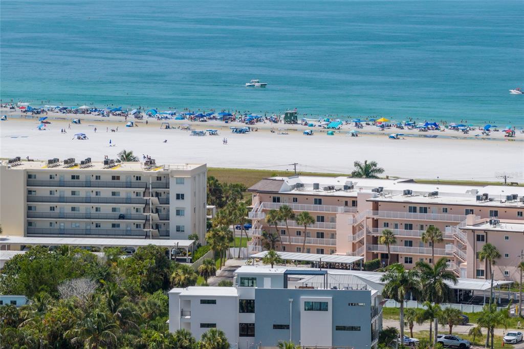 An elevated view of multi-story apartment buildings situated near a crowded sandy beach and ocean — 5547 AVENIDA DEL MARE, SARASOTA, FL