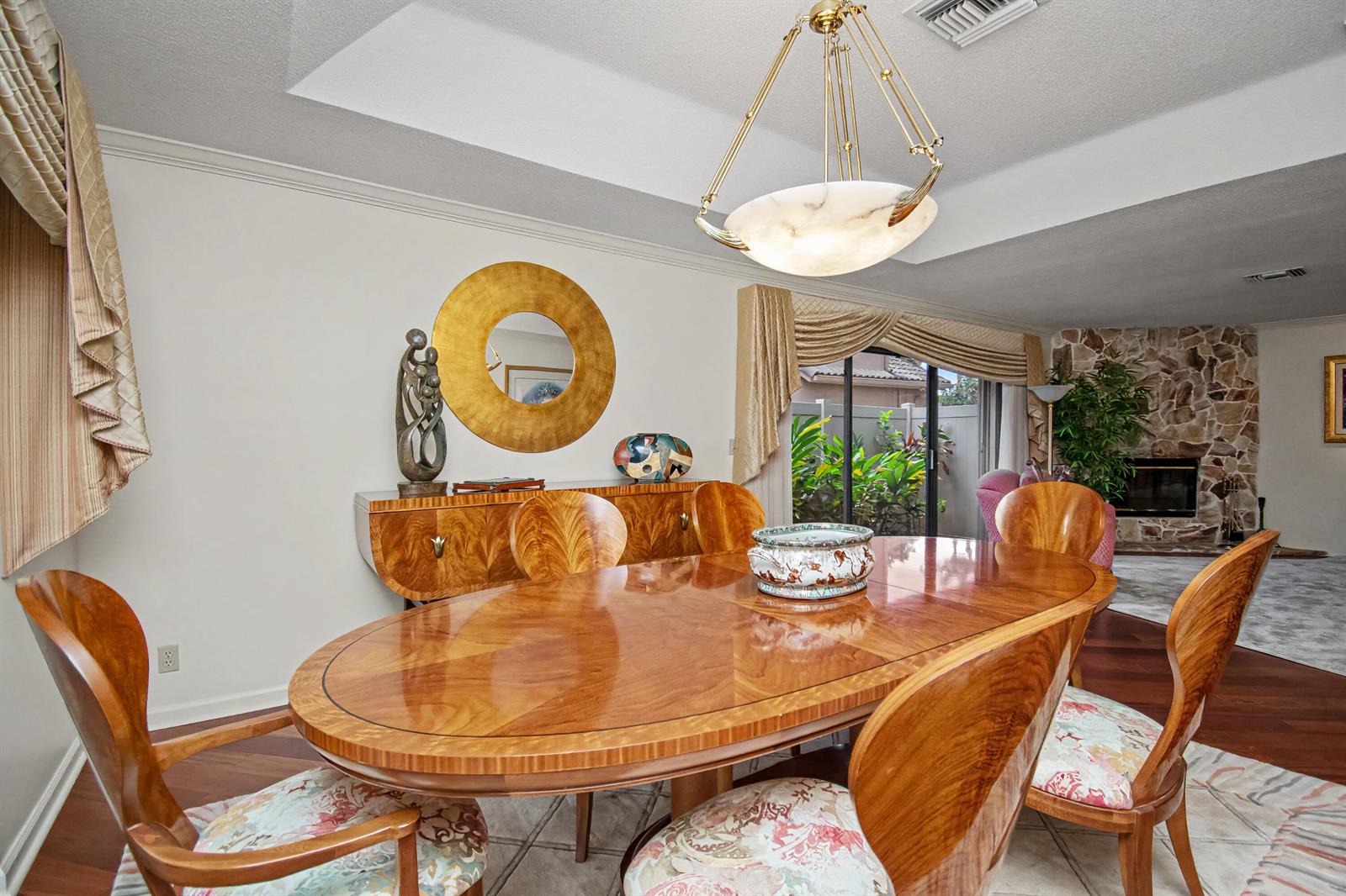 A dining room features a wooden oval table, matching chairs, a sideboard, and a chandelier — 7838 Tennyson Court, Boca Raton FL 33433, BOCA RATON, FL