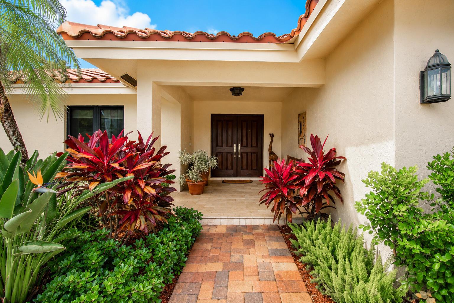 A paved walkway leads to the covered entryway of a house with double wooden doors — 7838 Tennyson Court, Boca Raton FL 33433, BOCA RATON, FL