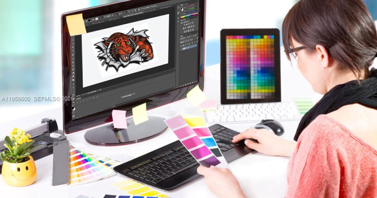 A person works at a desk with a computer monitor displaying a tiger graphic design — 8400 NW 33rd St, Doral FL 33122, DORAL, FL