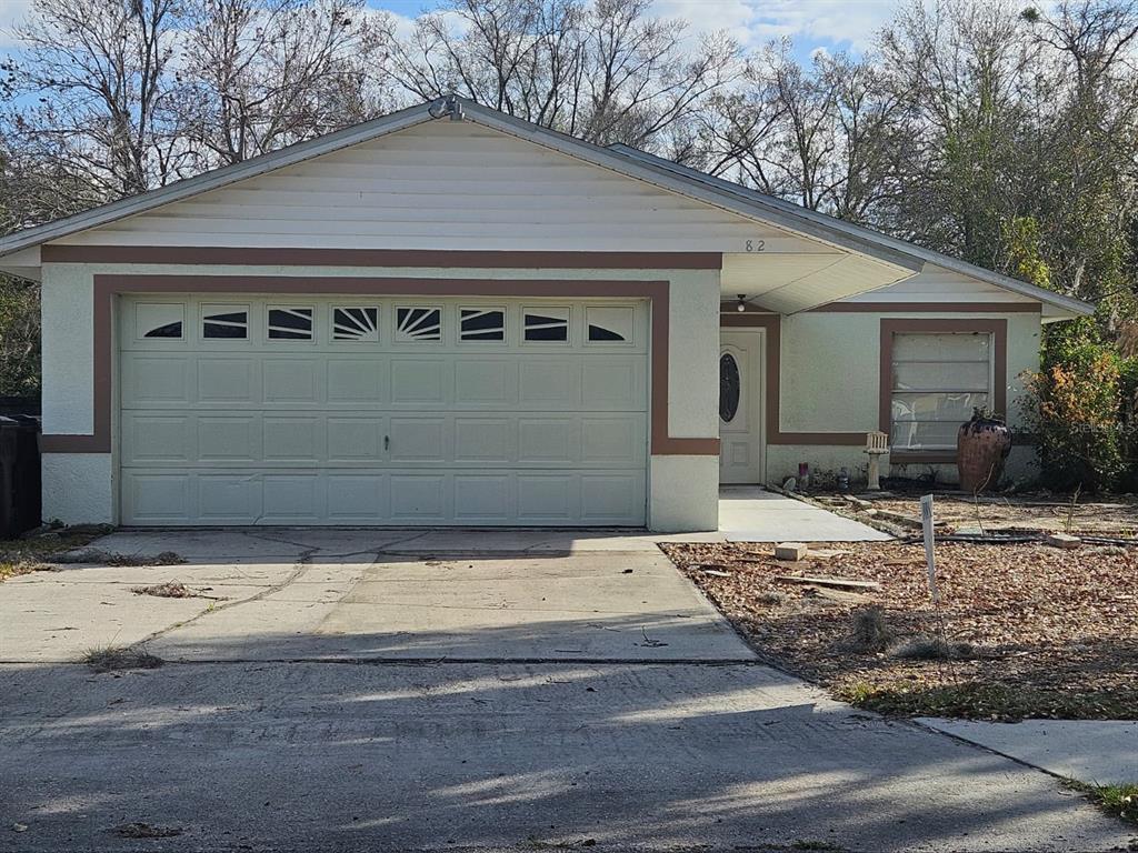 A single-story house with a two-car garage, light-colored stucco walls, and a concrete driveway — 1821 17TH STREET, ST CLOUD, FL