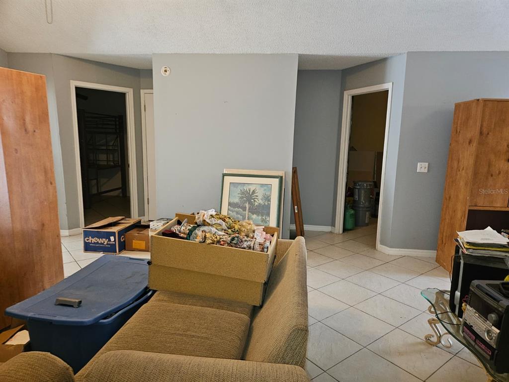 A living room with tiled floors, a couch, storage boxes, and two doorways — 1821 17TH STREET, ST CLOUD, FL