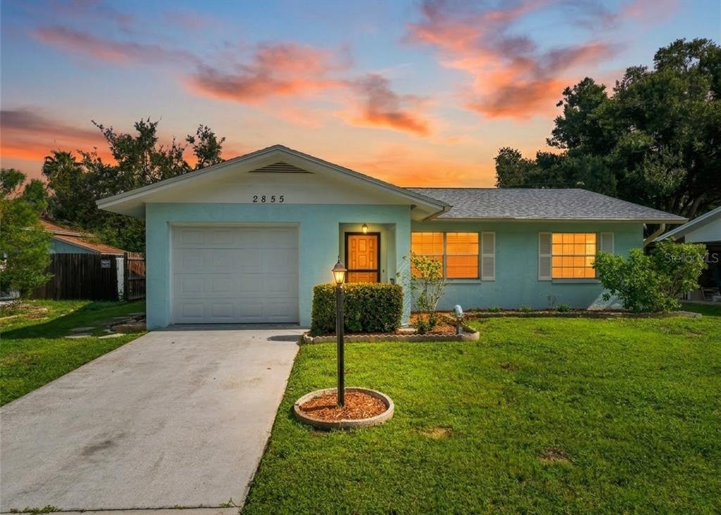 A light blue single-story house with a garage and a concrete driveway at sunset — 2855 DUEBY STREET, SARASOTA, FL