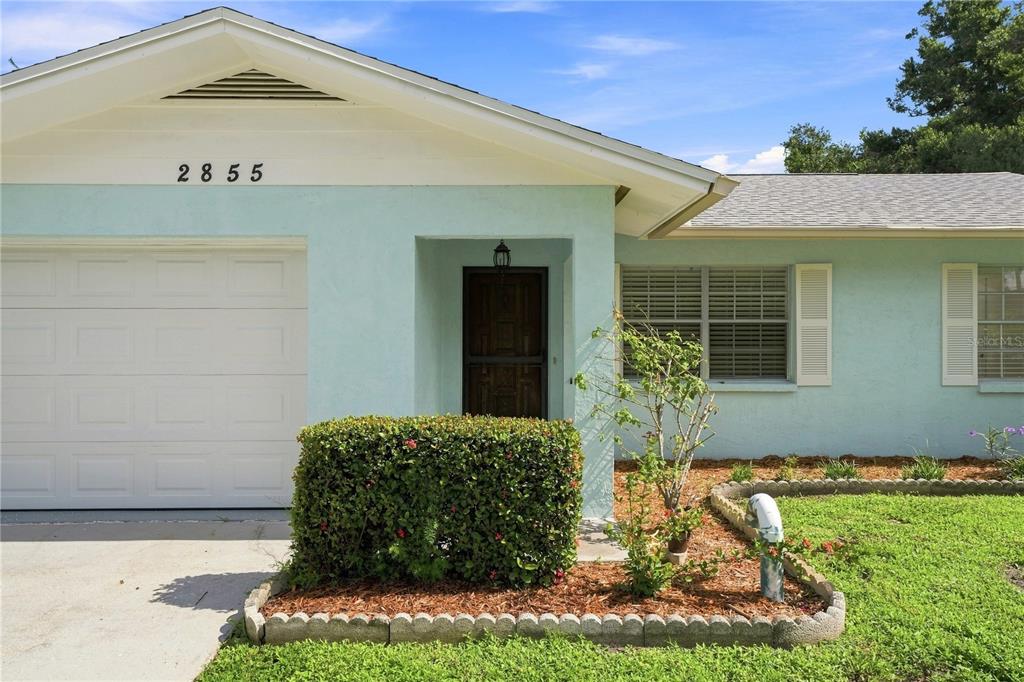 A light blue single-story house features a white garage door and a landscaped front yard — 2855 DUEBY STREET, SARASOTA, FL