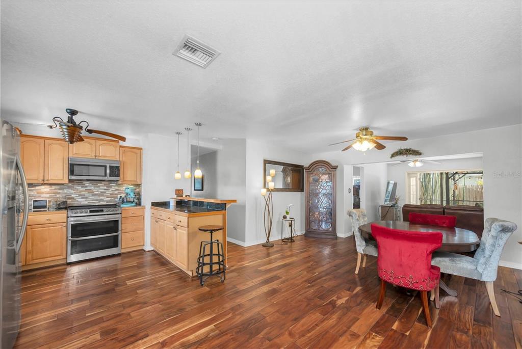 A kitchen and dining area with wood flooring, light wood cabinets, and a breakfast bar — 1700 74TH AVENUE N, ST PETERSBURG, FL