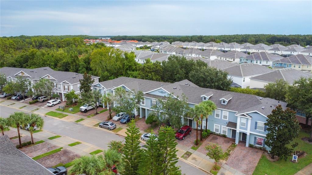 An aerial view shows a row of blue townhouses with driveways and surrounding suburban homes — 2412 CARAVELLE CIRCLE, KISSIMMEE, FL
