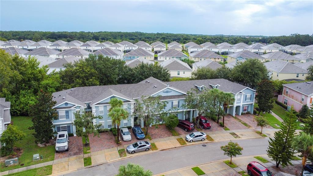 An aerial view shows a multi-unit townhouse building with brick driveways and surrounding suburban homes — 2412 CARAVELLE CIRCLE, KISSIMMEE, FL