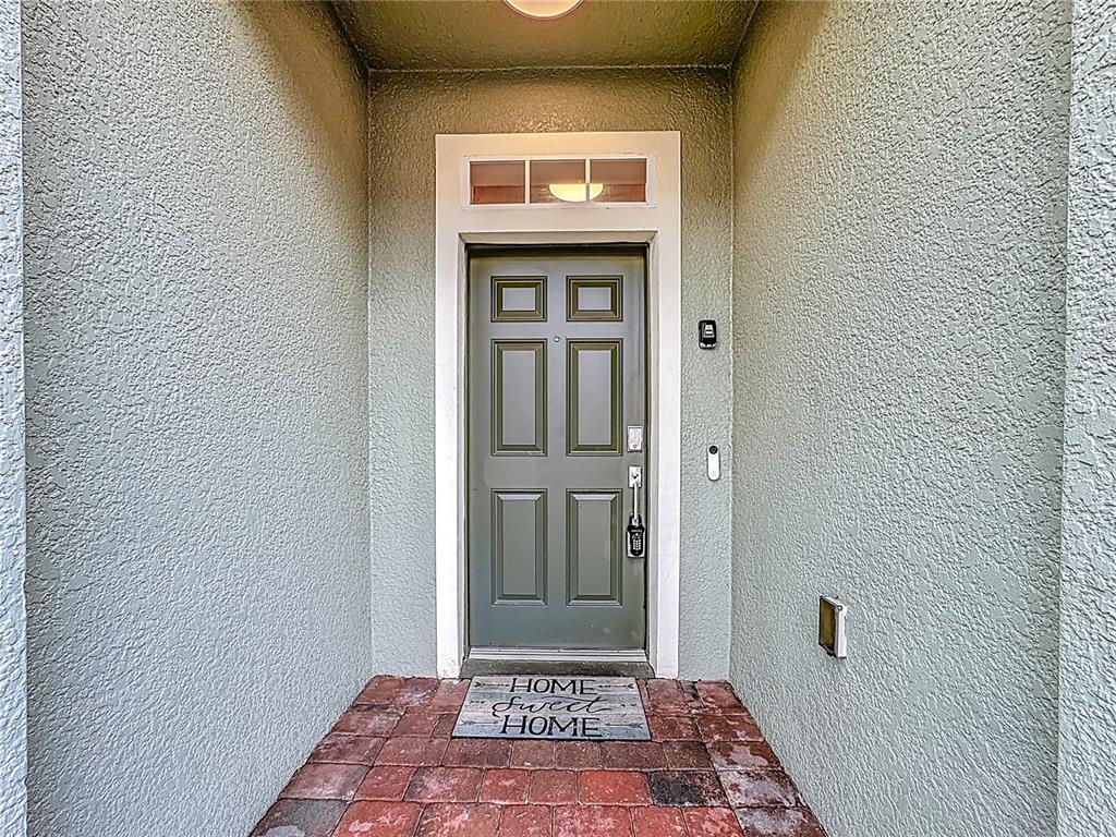 A front entryway features a green door with a transom window and a welcome mat — 2412 CARAVELLE CIRCLE, KISSIMMEE, FL