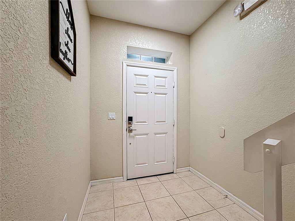 An entryway features a white front door, tiled flooring, and a staircase with a railing — 2412 CARAVELLE CIRCLE, KISSIMMEE, FL