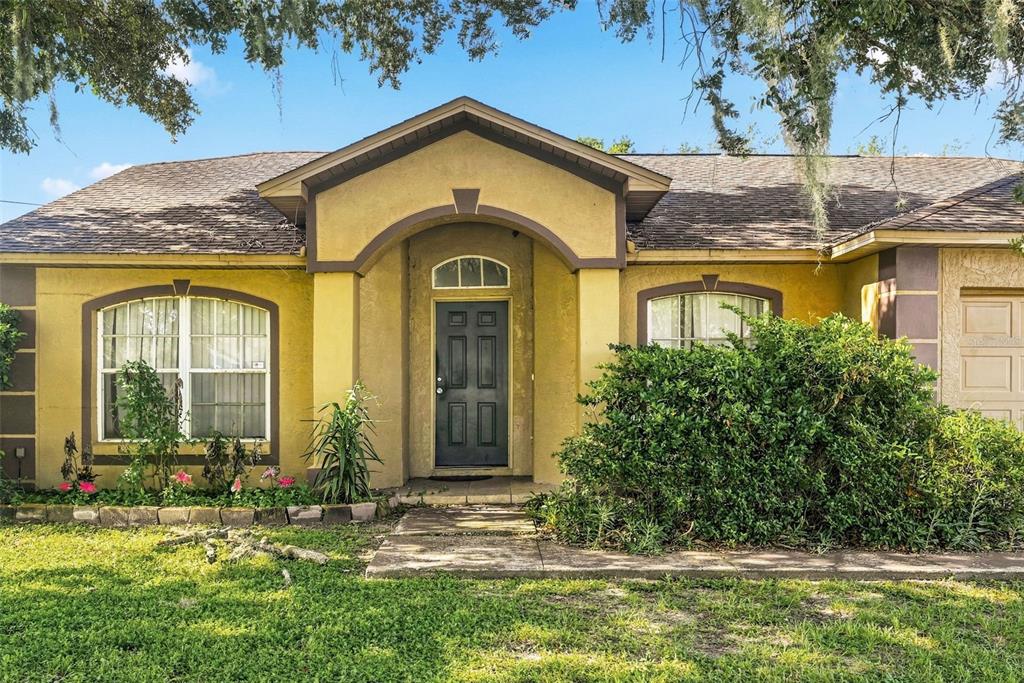 A single-story house with a yellow stucco exterior, a dark front door, and arched windows — 1593 WATSON OAKS COURT, LAKELAND, FL