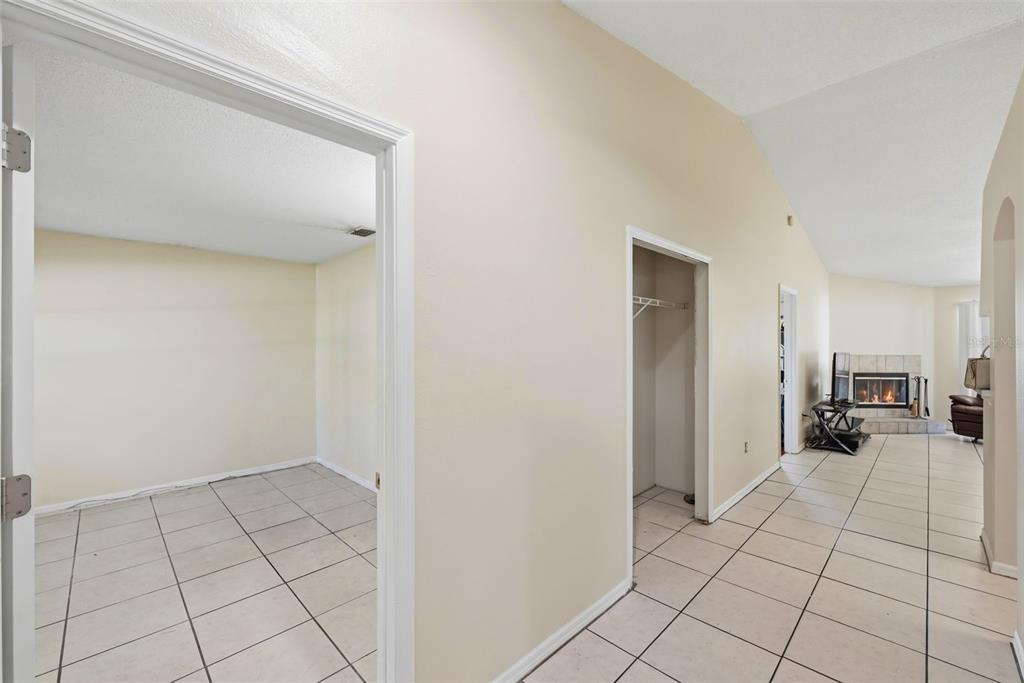 A hallway with tiled floors leads to a living room with a fireplace and closet — 1593 WATSON OAKS COURT, LAKELAND, FL
