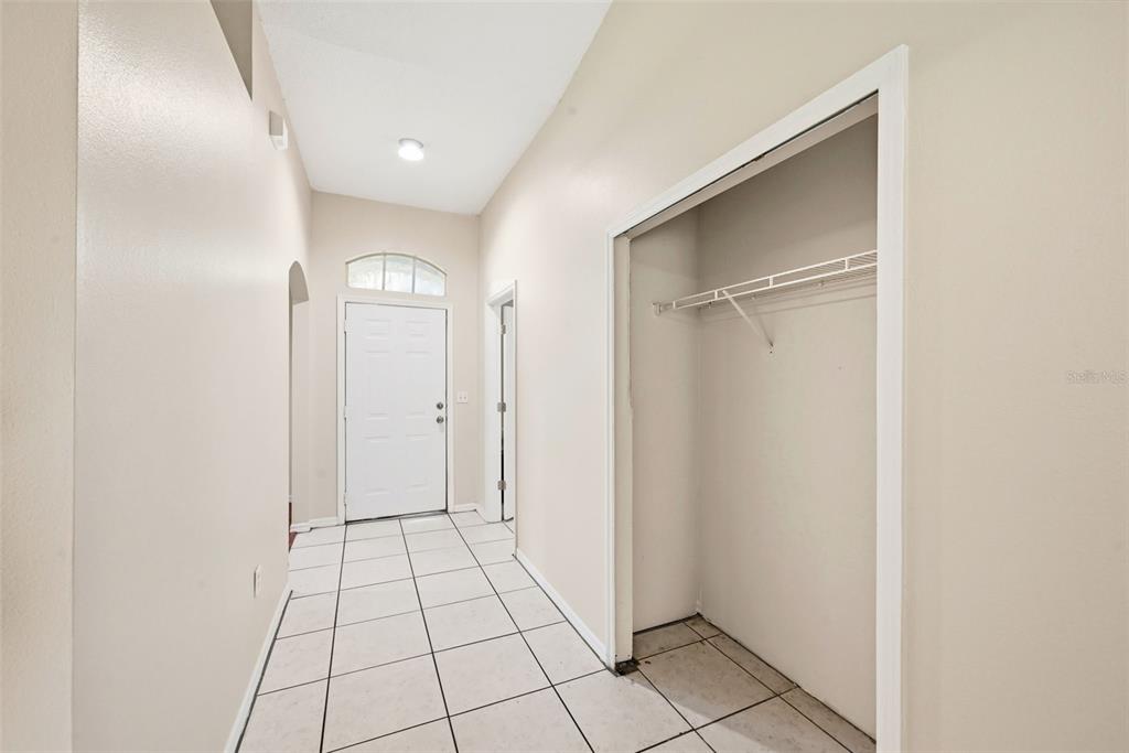 A tiled entryway features a white front door, a coat closet, and high ceilings — 1593 WATSON OAKS COURT, LAKELAND, FL