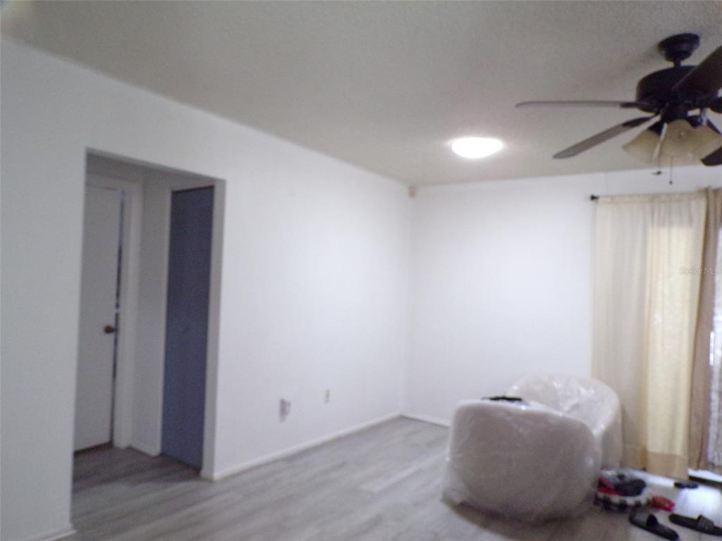 An empty room features white walls, light wood-look flooring, a ceiling fan, and a window — 304 OAK TRACK WAY, OCALA, FL