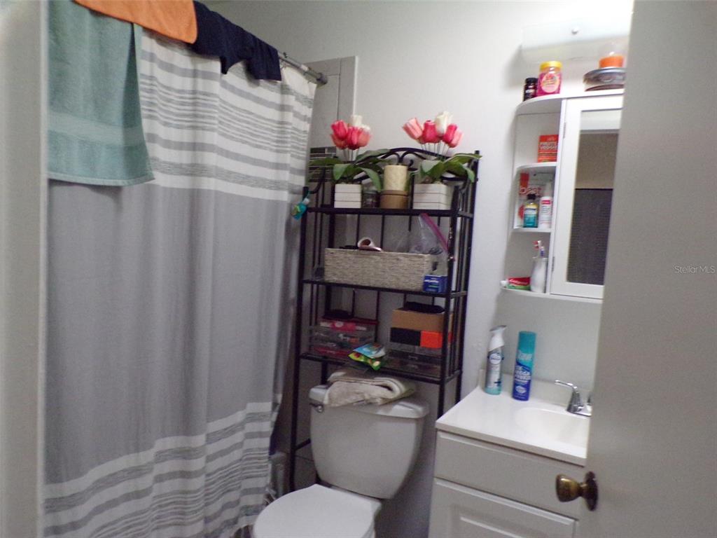 A bathroom features a toilet with a metal storage rack, a vanity, and a shower curtain — 304 OAK TRACK WAY, OCALA, FL