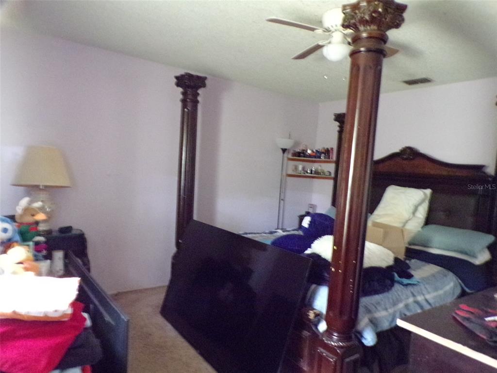 A bedroom features a four-poster bed, a large television, and a ceiling fan — 304 OAK TRACK WAY, OCALA, FL